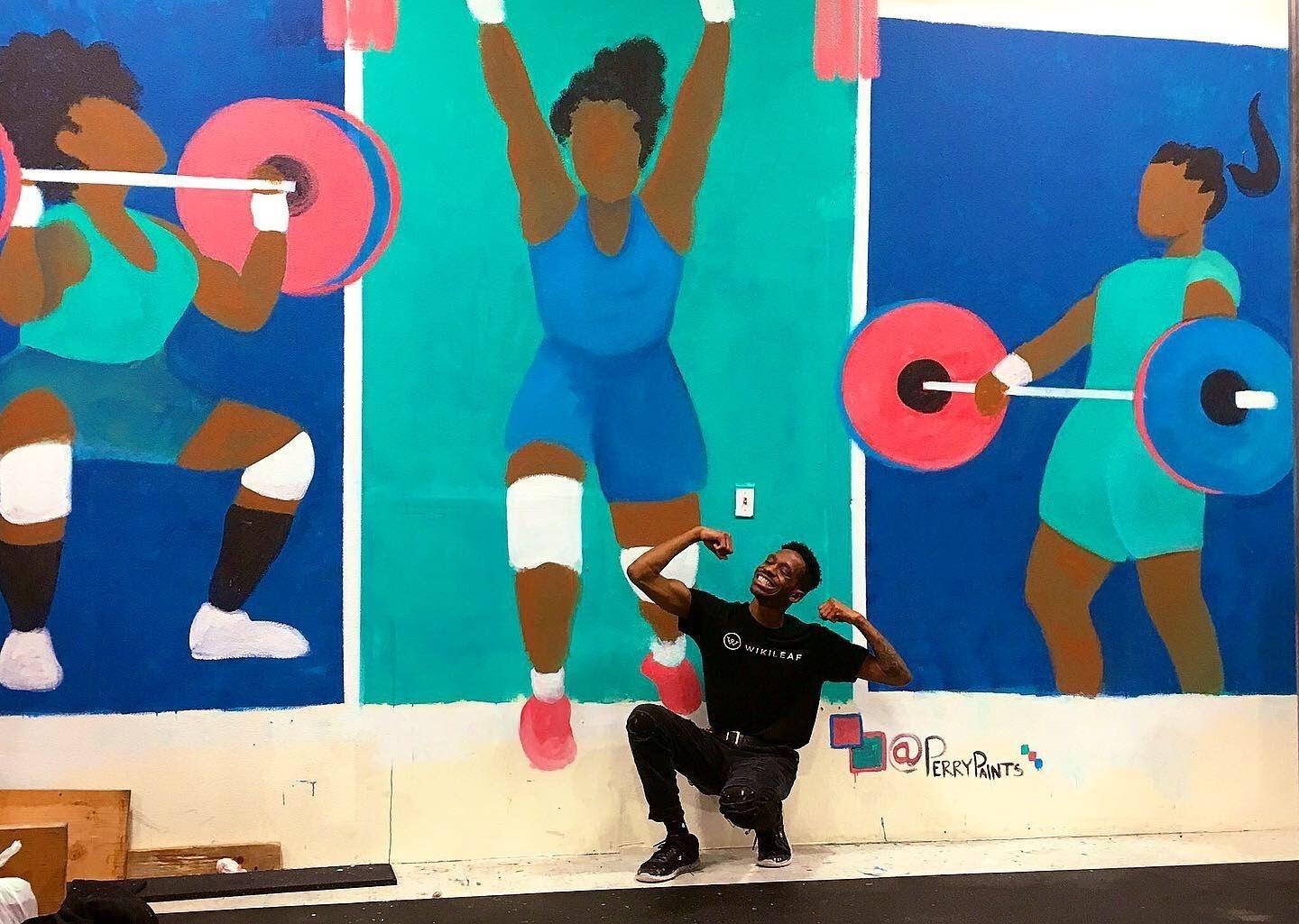 Perry Porter stands triumphantly in front of a mural painted in bright colors.