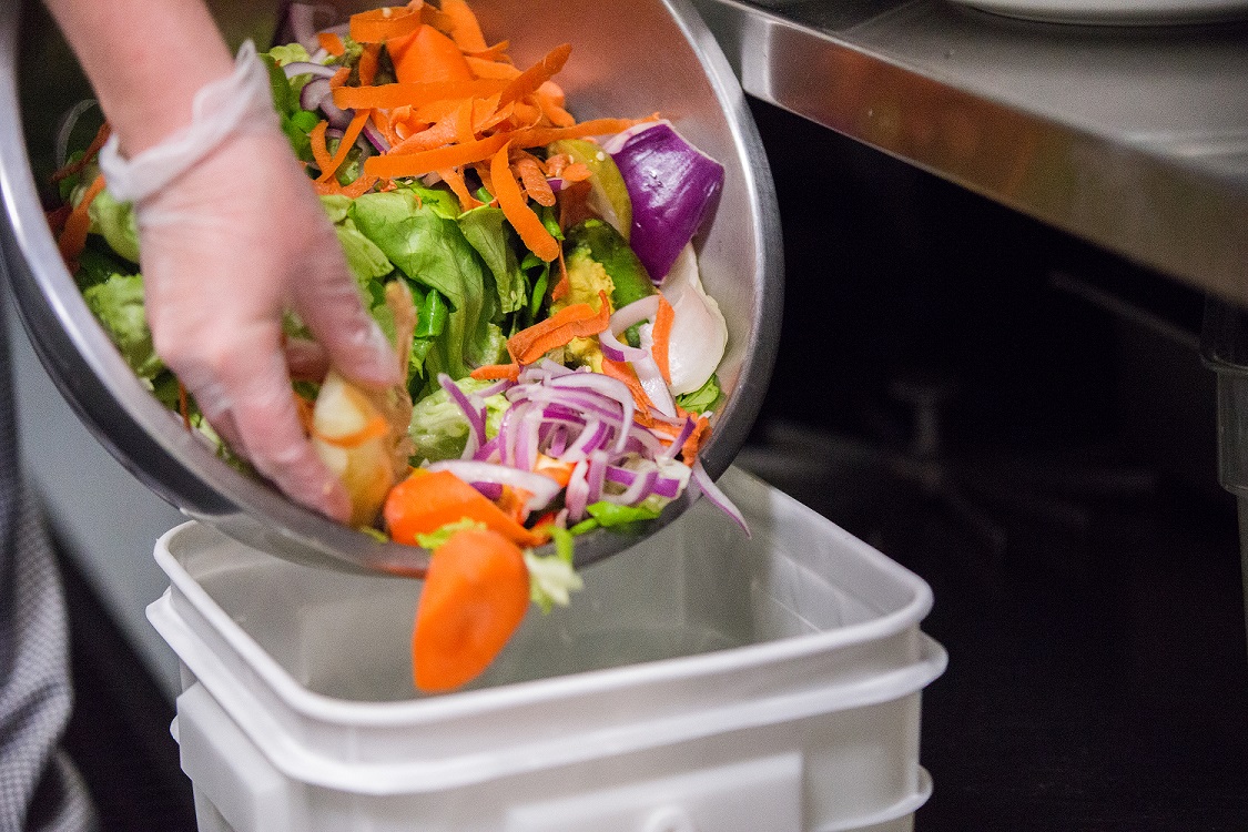 Chef dumping excess food into bucket Chef dumping excess food into bucket