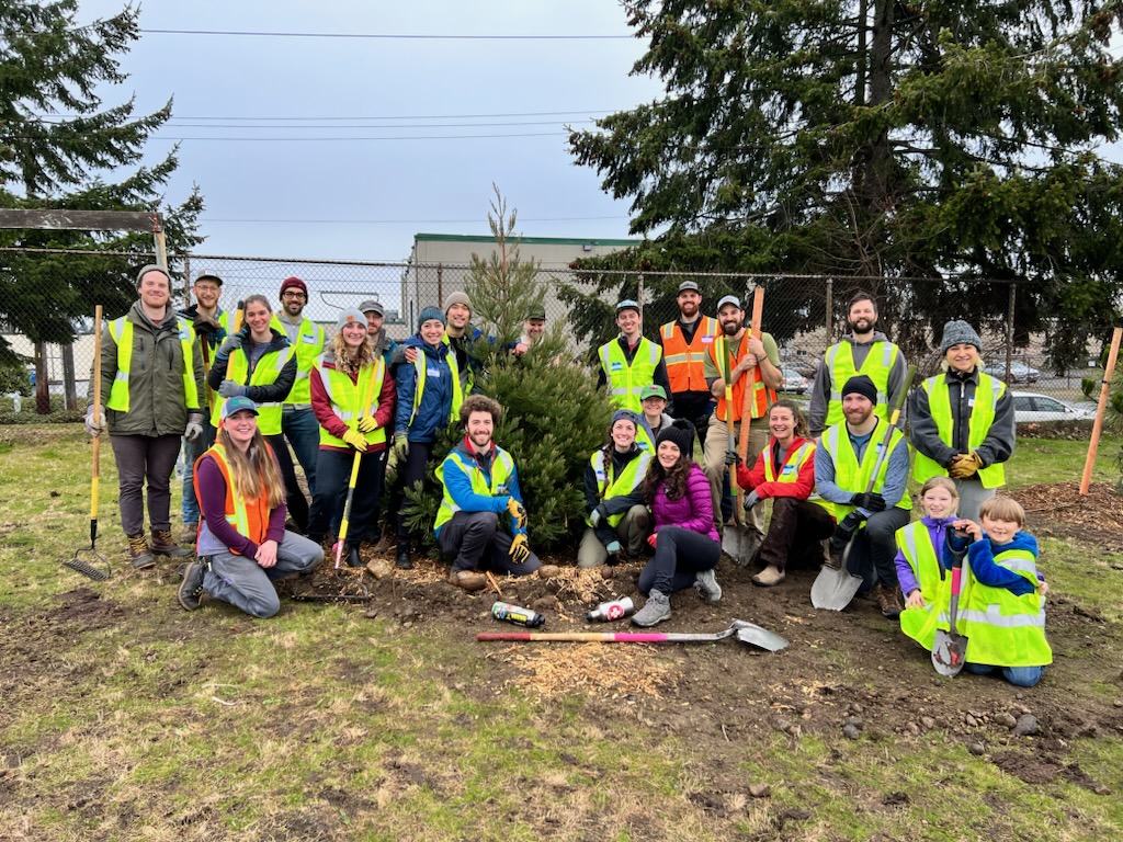 Volunteers posing in front of planted tree